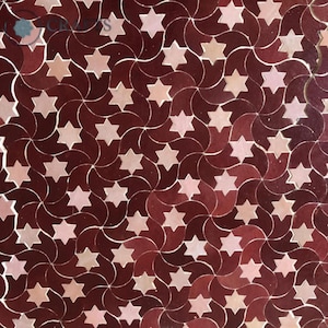 May include: Close-up of a decorative surface with a repeating pattern of six-pointed stars in shades of red and pink. The stars are set against a dark red background with curved lines, creating a swirling effect. The design is symmetrical.