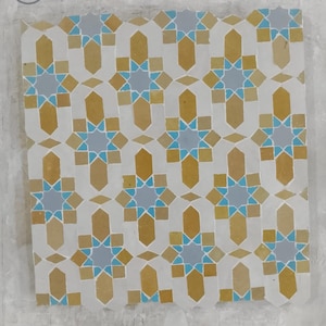 Puede incluir: Azulejo cuadrado con un patrón geométrico repetitivo en tonos amarillos, azules y grises. El azulejo tiene un fondo blanco y la palabra "CRAFTS" está en la esquina superior izquierda.