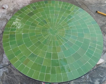 Puede incluir: Una mesa redonda de azulejos verdes con un patrón circular de azulejos en el centro.
