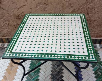 Puede incluir: Mesa cuadrada de mosaico con una tapa de patrón de diamantes blancos y verdes. La mesa tiene un marco y patas de metal negro. La mesa mide aproximadamente 76 cm cuadrados.