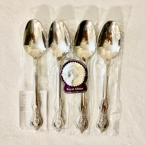 May include: Set of four silver spoons with ornate handles, packaged in clear plastic. The spoons are labeled "Royal Ailister".