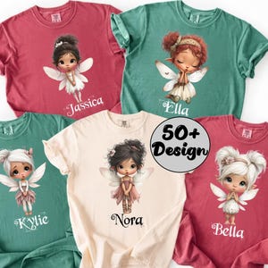 May include: A collection of five short-sleeved t-shirts in various colors: red, teal, and cream. Each shirt features a watercolor illustration of a fairy with personalized names: Jassica, Ella, Kylie, Nora, and Bella. The shirts also have the text "50+ Design".
