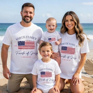 A family of four, consisting of a father, mother, and two children, posing together on a beach. They are all wearing matching white t-shirts with the text "Smith Family Fourth of July Cape Cod, MA" printed on them.