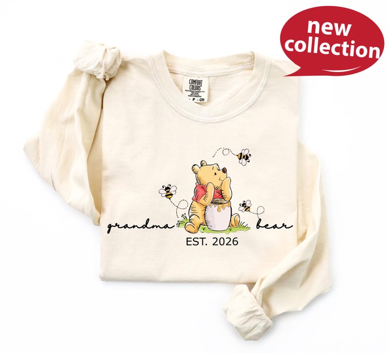 A white long-sleeved t-shirt with a Winnie the Pooh graphic and the text "Grandma Bear" printed on it.
