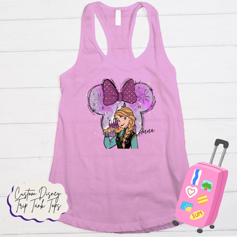 May include: A light pink tank top with a graphic of Anna from Frozen within a Mickey Mouse ear outline. The design includes a purple bow, snowflakes, and the name "Anna". A pink suitcase with travel stickers is in the image. Text on the bottom reads "Custom Disney Trip Tank Tops."
