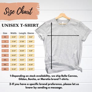 Puede incluir: Una camiseta unisex gris claro colgada de una percha de madera. La imagen incluye una tabla de tallas con medidas en pulgadas para el ancho, el largo y el largo de la manga. El texto de la imagen dice "UNISEX T-SHIRT" y "Size Chart."