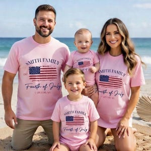 A family of four, consisting of a man, a woman, and two children, posing together on a beach. They are all wearing matching pink t-shirts with the text "Smith Family Fourth of July Cape Cod, MA" printed on them.