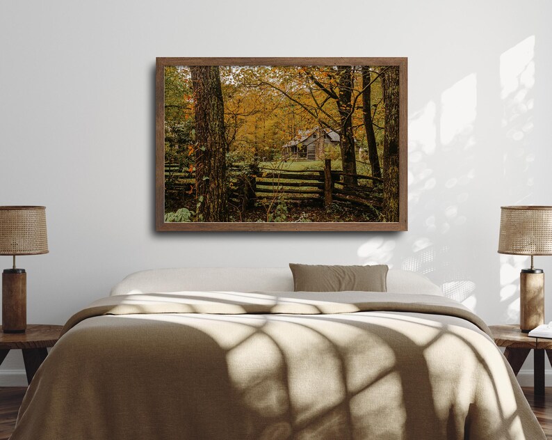 May include: A rustic wooden cabin nestled in a forest with vibrant autumn foliage. The cabin has a wooden fence and is surrounded by trees with yellow, orange, and red leaves.