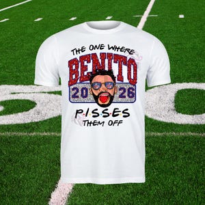 Puede incluir: Camiseta blanca con un diseño gráfico. El diseño incluye el texto "THE ONE WHERE BENITO 2026 PISSES THEM OFF". La palabra "BENITO" está en letras rojas con purpurina. El gráfico incluye una cara de dibujos animados con gafas de sol.