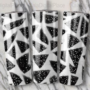 Könnte beinhalten: Drei Edelstahlbecher mit einem schwarz-weißen geometrischen Design. Das Design zeigt schwarze Dreiecke mit weißen Punkten auf weißem Hintergrund. Die Becher sind zylindrisch und haben einen silbernen Rand.