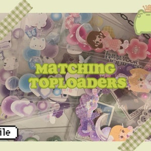 May include: A collection of clear plastic top loaders with colourful stickers and embellishments inside. The top loaders are arranged in a pile and some are partially overlapping. The text "Matching Toploaders" is written in bold, white letters on a green background. The text "smile" is written in white letters on a green background.
