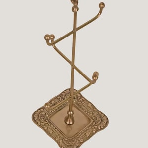 Suporte artesanal em latão para exibição de joias e acessórios, com ponteira ornamentada e múltiplos ganchos. imagem 5