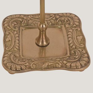 Suporte artesanal em latão para exibição de joias e acessórios, com ponteira ornamentada e múltiplos ganchos. imagem 4