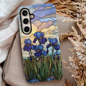 May include: A phone case with a stained glass design featuring blue iris flowers and a sunset sky.