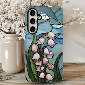 Pu&ograve; includere: Una custodia per telefono con un designo in vetro colorato che presenta un bouquet di gigli bianchi su uno sfondo blu.