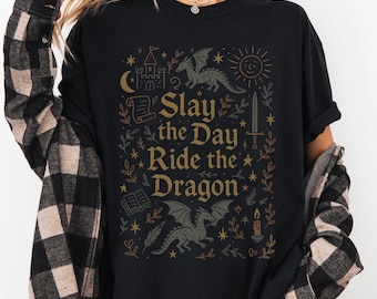 May include: Black t-shirt with a graphic design featuring a dragon, a castle, a sword, and the text "Slay the Day Ride the Dragon".