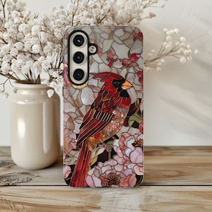 May include: A phone case with a stained glass design featuring a red cardinal bird and pink flowers.