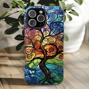 May include: A colorful phone case with a stained glass design of a tree with swirling branches. The case is black and has a cutout for the camera lens.