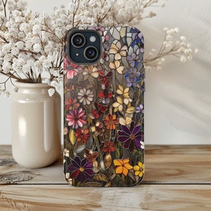 May include: A clear phone case with a colourful floral design. The case features a variety of flowers in shades of pink, purple, blue, and yellow. The case is designed for an iPhone.