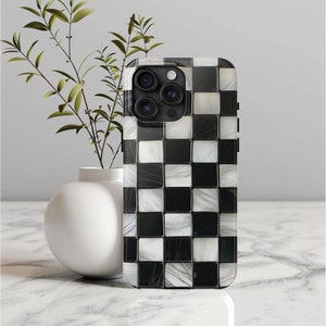 May include: A black and white checkered phone case with a mosaic tile design. The case has a raised camera bump with three lenses.