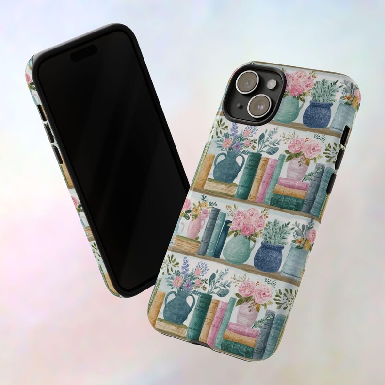 Peut inclure: Un smartphone noir et une coque de t&eacute;l&eacute;phone avec un motif aquarelle. La coque pr&eacute;sente une biblioth&egrave;que avec des vases de fleurs et des piles de livres roses, bleus et verts.