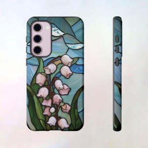 Pu&ograve; includere: Una custodia per telefono con un designo a vetri colorati che presenta un bouquet di mughetti in tonalit&agrave; rosa e bianche su uno sfondo blu e verde.