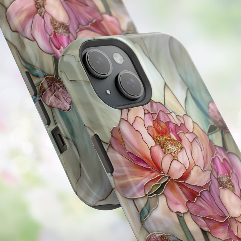 May include: A phone case with a floral design featuring pink peonies on a green and white background. The case has a camera cutout and a black border.