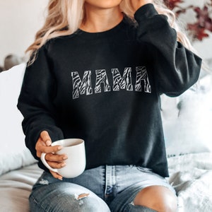May include: Black sweatshirt with a zebra print "MAMA" graphic.