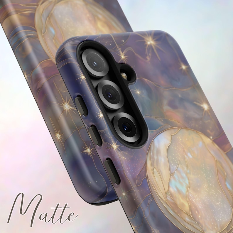 Puede incluir: Funda de tel&eacute;fono mate con un dise&ntilde;o celestial. La funda presenta un patr&oacute;n arremolinado de azules, p&uacute;rpuras y dorados, con acentos de estrellas. La palabra "Matte" est&aacute; impresa en cursiva en la parte inferior. La funda tiene un recorte para una c&aacute;mara de triple lente.