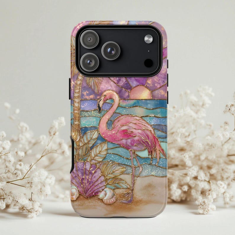 Puede incluir: Funda de tel&eacute;fono con un flamenco rosa en una playa con un atardecer. El dise&ntilde;o incluye palmeras, conchas marinas y un oc&eacute;ano colorido, con un contorno dorado. La funda tiene un acabado brillante.