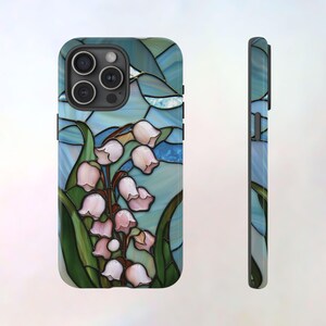 Pu&ograve; includere: Una custodia per telefono con un designo a vetri colorati che presenta un bouquet di mughetti rosa su uno sfondo blu e verde.