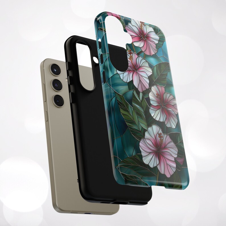 May include: A phone case with a floral design. The case is black with a clear back that shows a pattern of pink hibiscus flowers on a teal background.