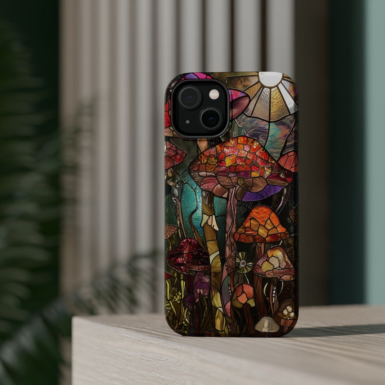May include: A colorful phone case with a stained glass design of mushrooms in shades of red, orange, purple, and green. The case has a black background and a clear protective layer.