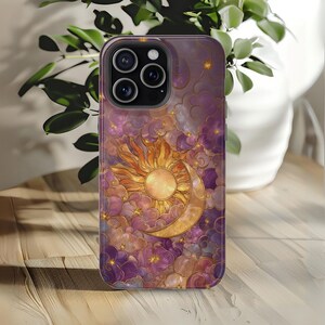 May include: A phone case with a celestial design. It features a golden sun and crescent moon set against a backdrop of purple clouds and stars. The case has a glossy finish and a protective bumper.