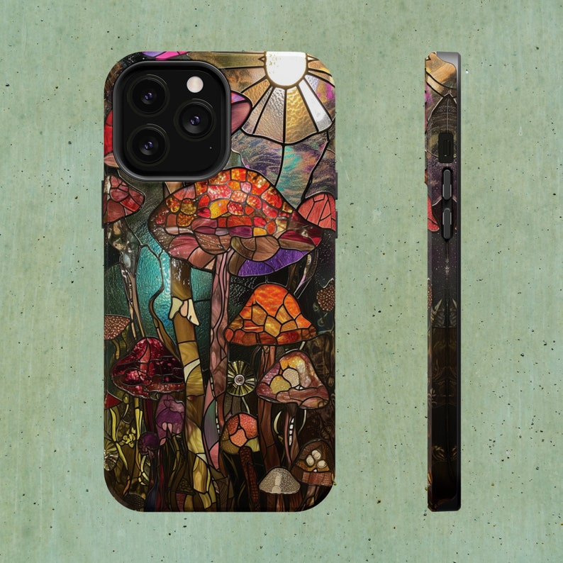 May include: A colorful phone case with a stained glass design featuring mushrooms in shades of red, orange, yellow, and green. The case has a black border and a clear back.