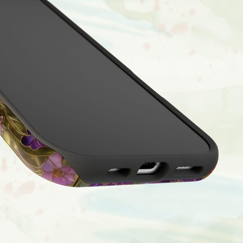Op de afbeelding: Zwarte smartphonehoes met een bloemenpatroon. De hoes heeft een zwart frame en een kleurrijk ontwerp van paarse en gouden bloemen. Het patroon loopt rond de randen van de telefoon.
