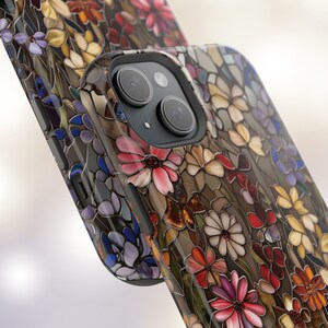 May include: A phone case with a stained glass design featuring colourful flowers and a butterfly. The case is black and has a camera lens cutout.