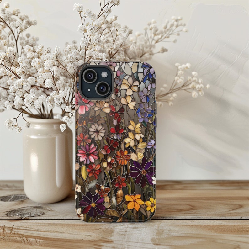May include: A clear phone case with a colourful floral design. The case features a variety of flowers in shades of pink, purple, blue, and yellow. The case is designed for an iPhone.