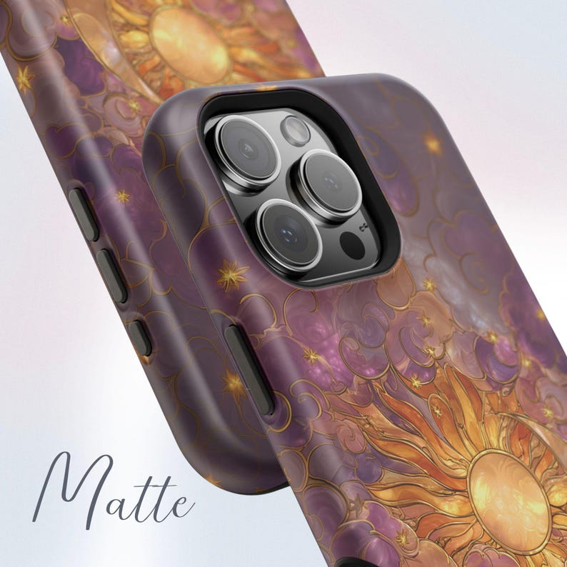 May include: Matte phone case with a celestial design featuring a sun, stars, and clouds in purple, gold, and orange hues. The case has a black border and a matte finish. The word "Matte" is written in cursive.