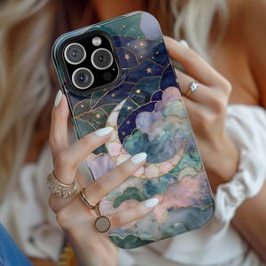 May include: A smartphone case with a celestial design. The case features a crescent moon, stars, and clouds in shades of blue, green, and pink, accented with gold detailing. The case has a glossy finish and a camera cutout.