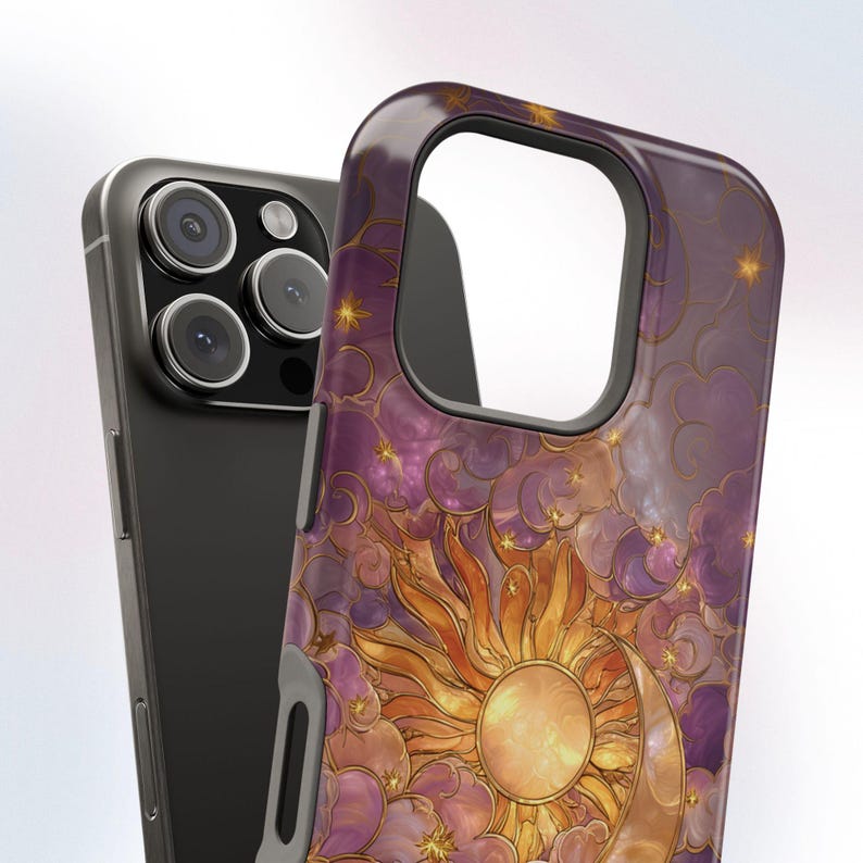 May include: A phone case with a celestial design. The case features a vibrant sun and crescent moon illustration in shades of orange and gold, set against a purple and pink cloudy background. The case is designed to fit a smartphone.