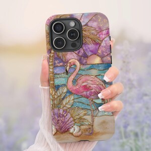 Puede incluir: Funda de tel&eacute;fono con un flamenco rosa sobre una escena de playa con puesta de sol, palmera y conchas marinas. La funda tiene un efecto de vidriera con detalles dorados y un acabado texturizado.