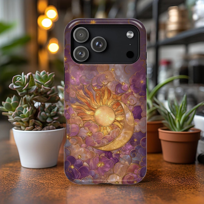 May include: A phone case with a celestial design. It features a sun and crescent moon set against purple clouds. The case has a glossy finish and a camera cutout.