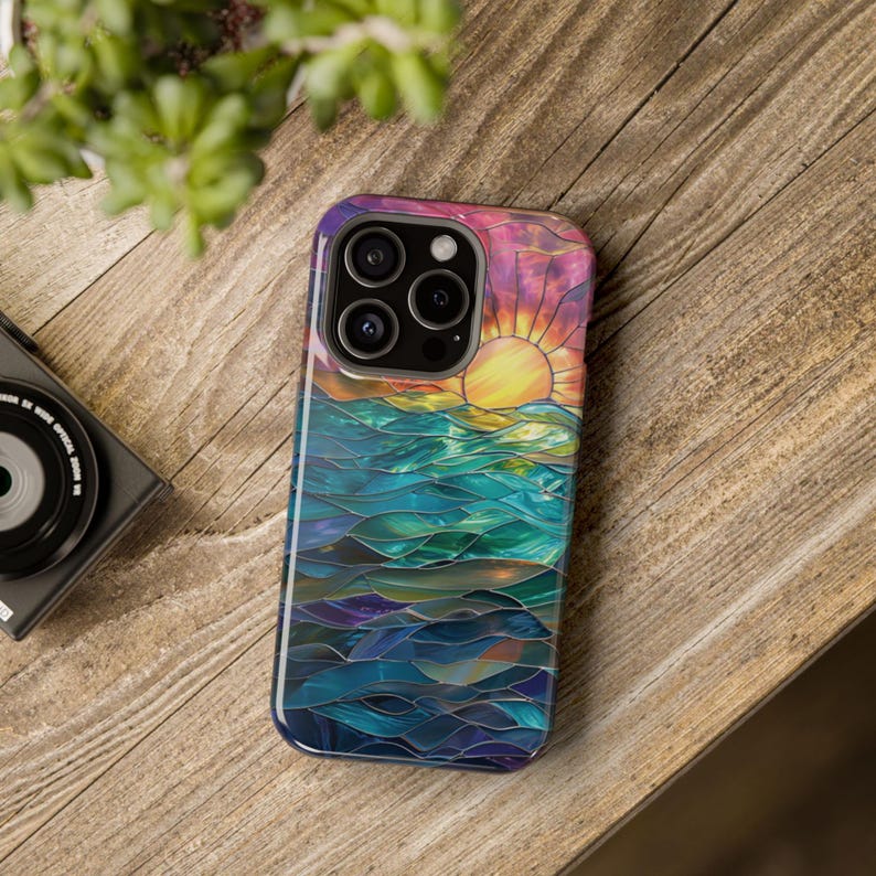 Puede incluir: Una funda de tel&eacute;fono colorida con un dise&ntilde;o de vitral de una puesta de sol sobre el oc&eacute;ano. La funda tiene un esquema de color azul, verde, morado y naranja.