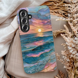 May include: A phone case featuring a sunset over the ocean design. The case has a vibrant color palette of blues, pinks, and gold, with a textured, stained-glass effect. The phone case has a camera module with three lenses.