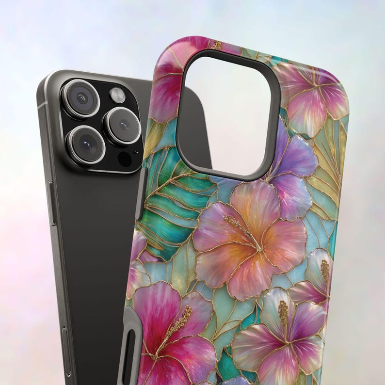 May include: A smartphone case featuring a vibrant floral pattern of pink, orange, and purple hibiscus flowers with green leaves, all outlined in gold. The case has a large cutout for the camera module and is shown next to a dark gray smartphone.