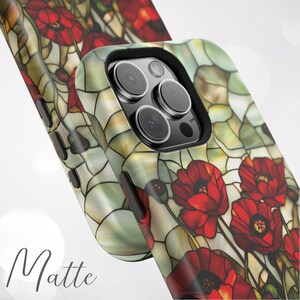 Pu&ograve; includere: Una custodia per telefono opaca con un design a vetri colorati con papaveri rossi su uno sfondo verde e bianco. La custodia ha un ritaglio per gli obiettivi della fotocamera del telefono.