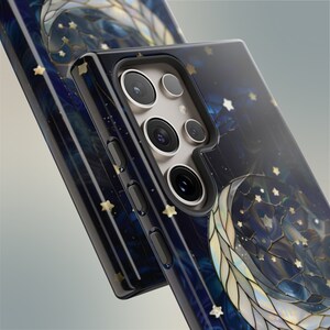 Puede incluir: Una funda de tel&eacute;fono negra con un dise&ntilde;o de luna y estrellas de vidrio emplomado dorado y azul. La funda tiene una protuberancia de c&aacute;mara elevada con tres lentes.