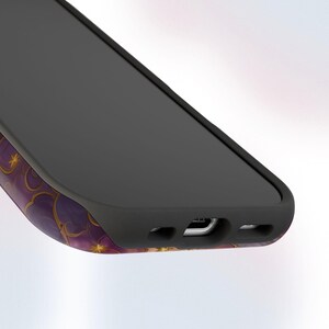 May include: A black smartphone with a purple and gold floral design on the side. The phone has a black screen and a black protective case. The design features gold stars and a repeating floral pattern.
