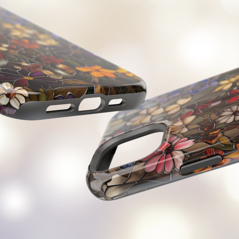May include: Two phone cases featuring a floral design. The cases are black with a clear back that reveals a colourful stained glass style floral pattern.